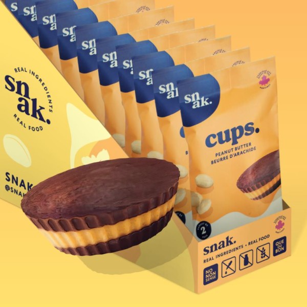 A snak. peanut butter cup sits in front of a case of cups, all neatly packaged